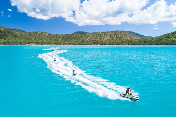 A jet ski cutting a long white wake across turquoise water in the Whitsundays
